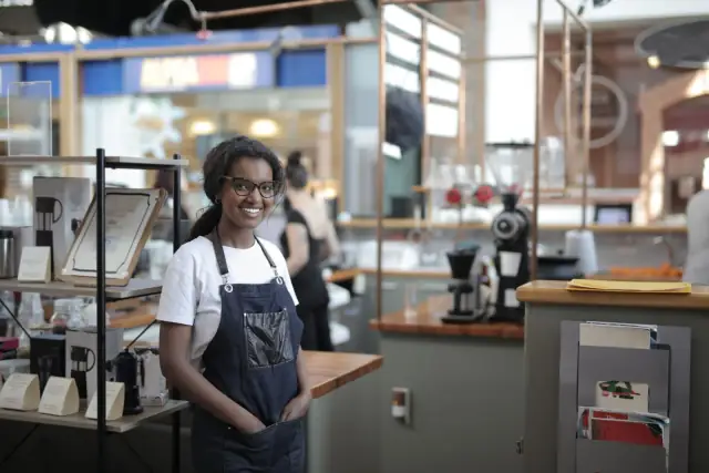 Gérante de café souriante en tablier dans son établissement