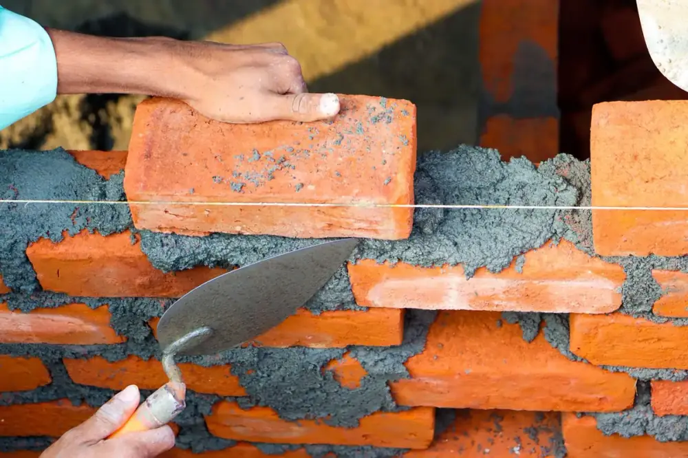 Maçon posant des briques au mortier sur un chantier