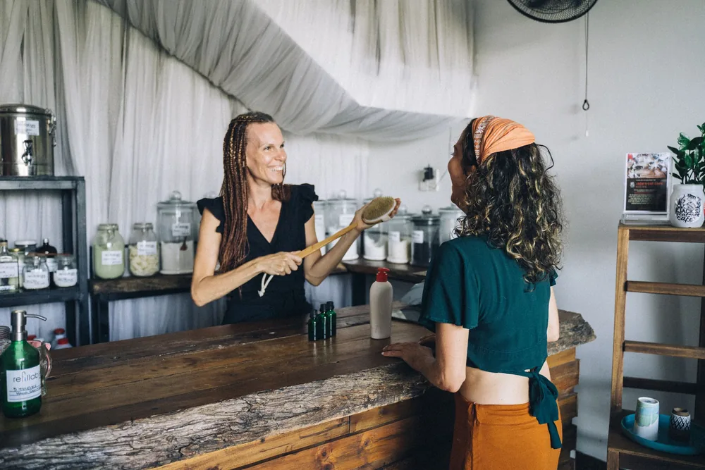 Commerçante souriante accueillant une cliente au comptoir de son épicerie