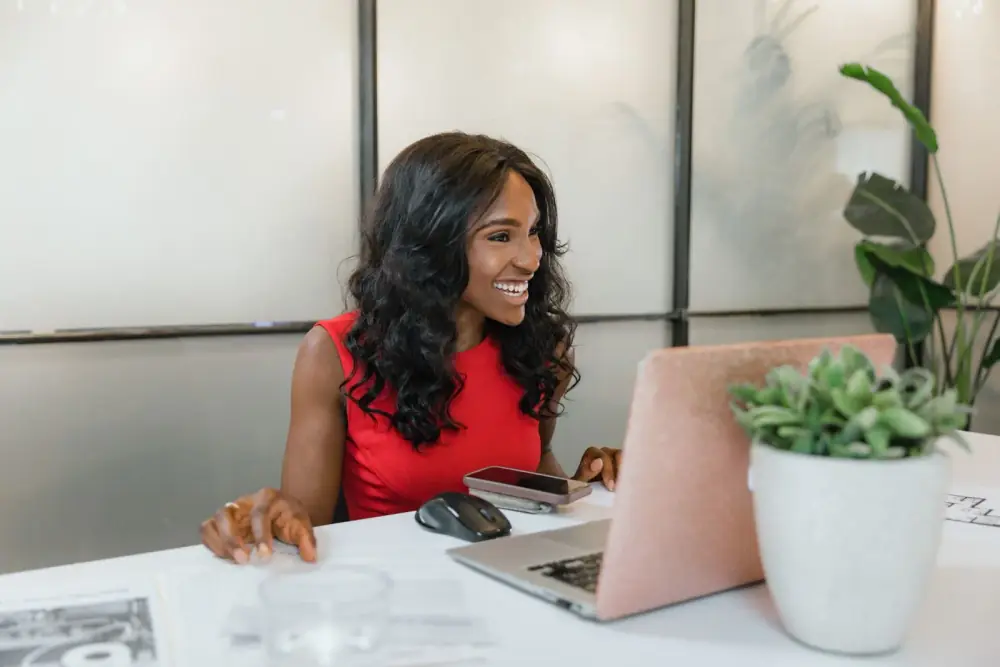 Entrepreneure souriante travaillant sur son ordinateur et son smartphone