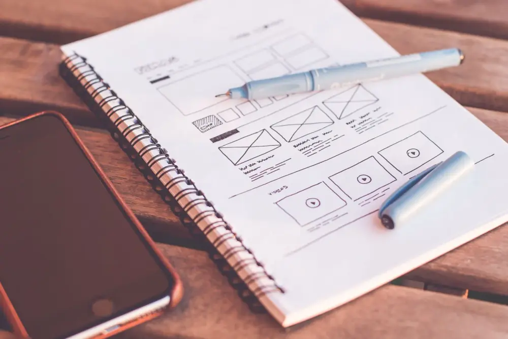 Croquis de maquette de site web dessinés dans un carnet à côté d'un smartphone