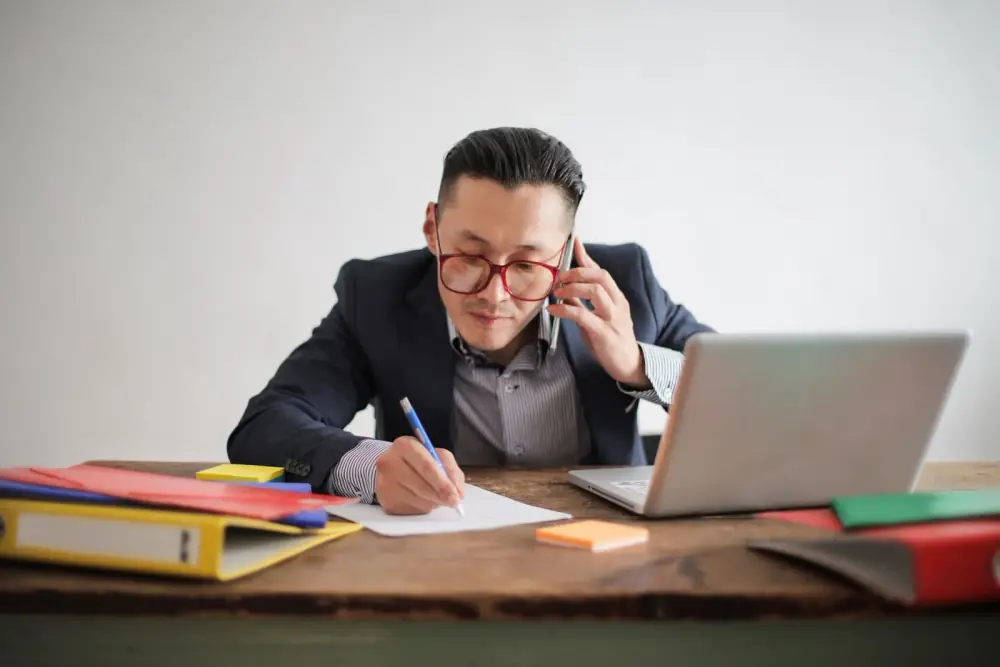 Professionnel au téléphone prenant des notes à son bureau