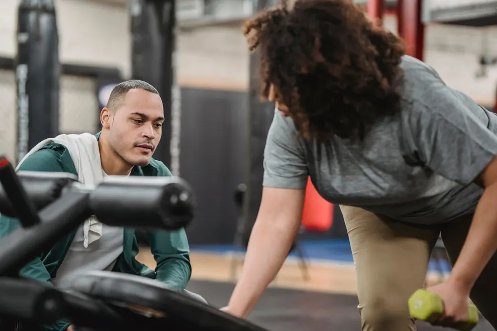 Coach sportif guidant une cliente pendant une séance d'entraînement