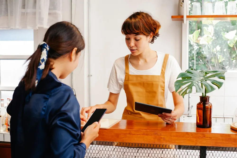 Commerçante et cliente échangeant autour d'une tablette au comptoir