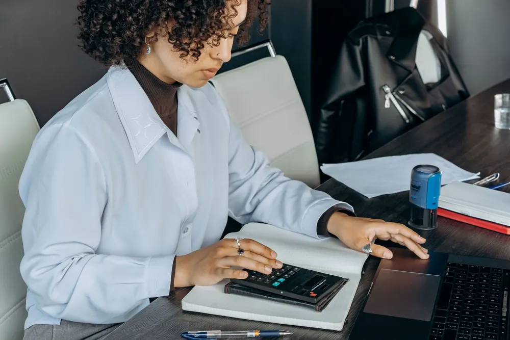Comptable effectuant des calculs sur sa calculatrice à son bureau