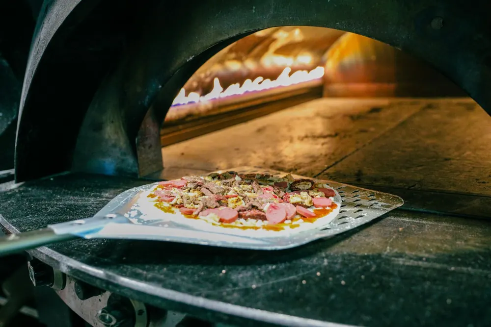 Pizza enfournée dans le four à bois d'une pizzeria