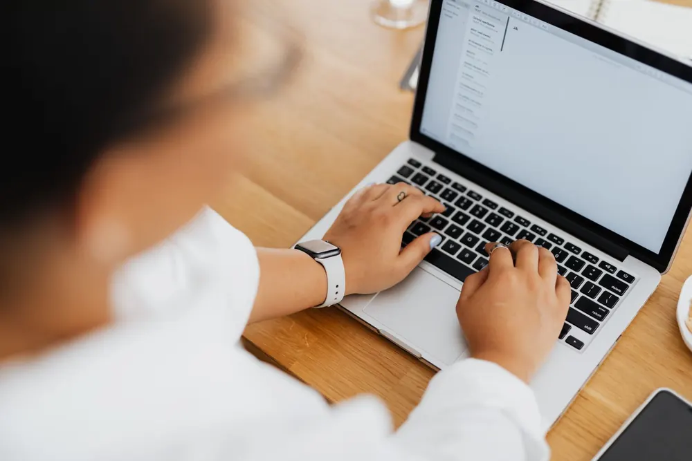 Mains tapant un message sur le clavier d'un ordinateur portable