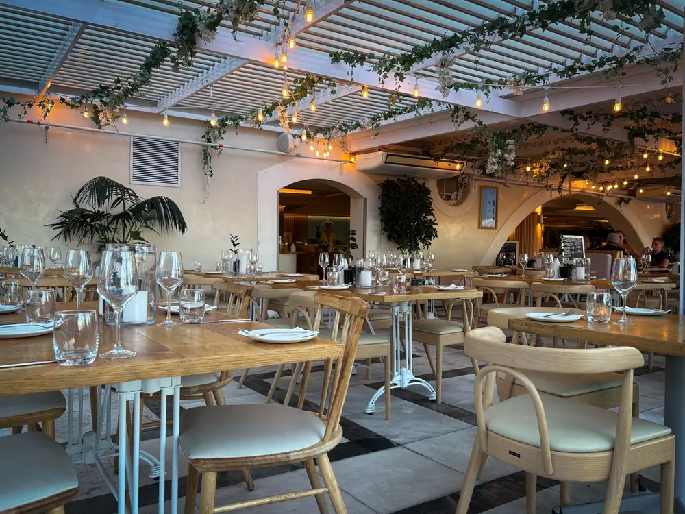 Salle de restaurant chaleureuse avec tables dressées et guirlandes lumineuses