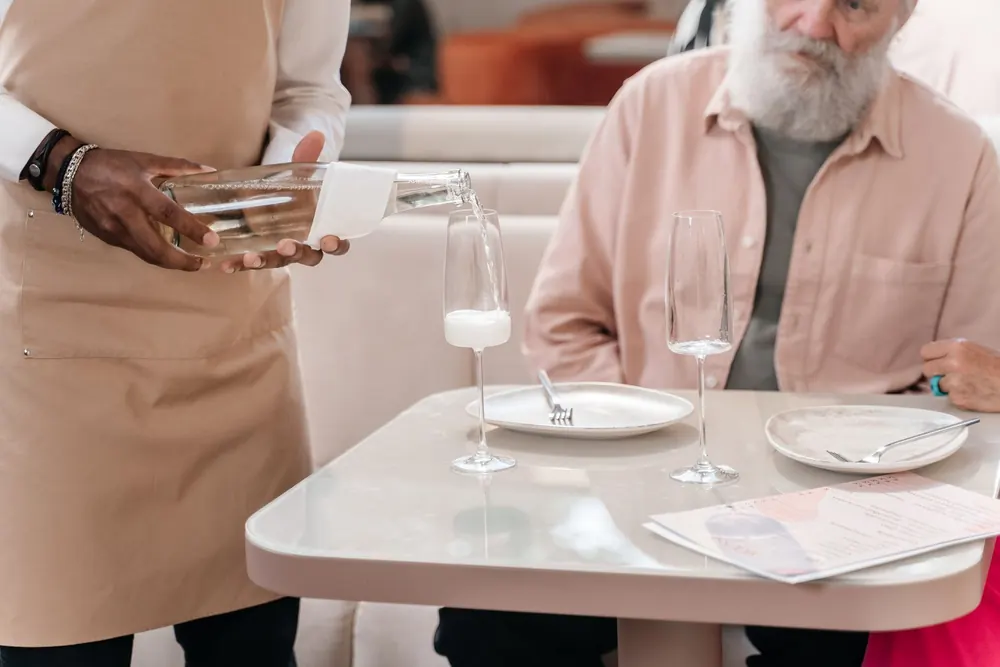Serveur versant de l'eau à un client attablé dans un restaurant