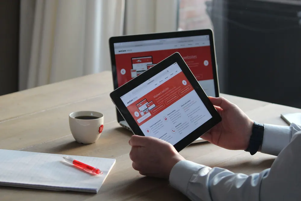 Professionnel consultant un site web sur sa tablette devant son ordinateur